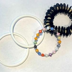 Plastic bracelets, two white, one black/white, one multicolored